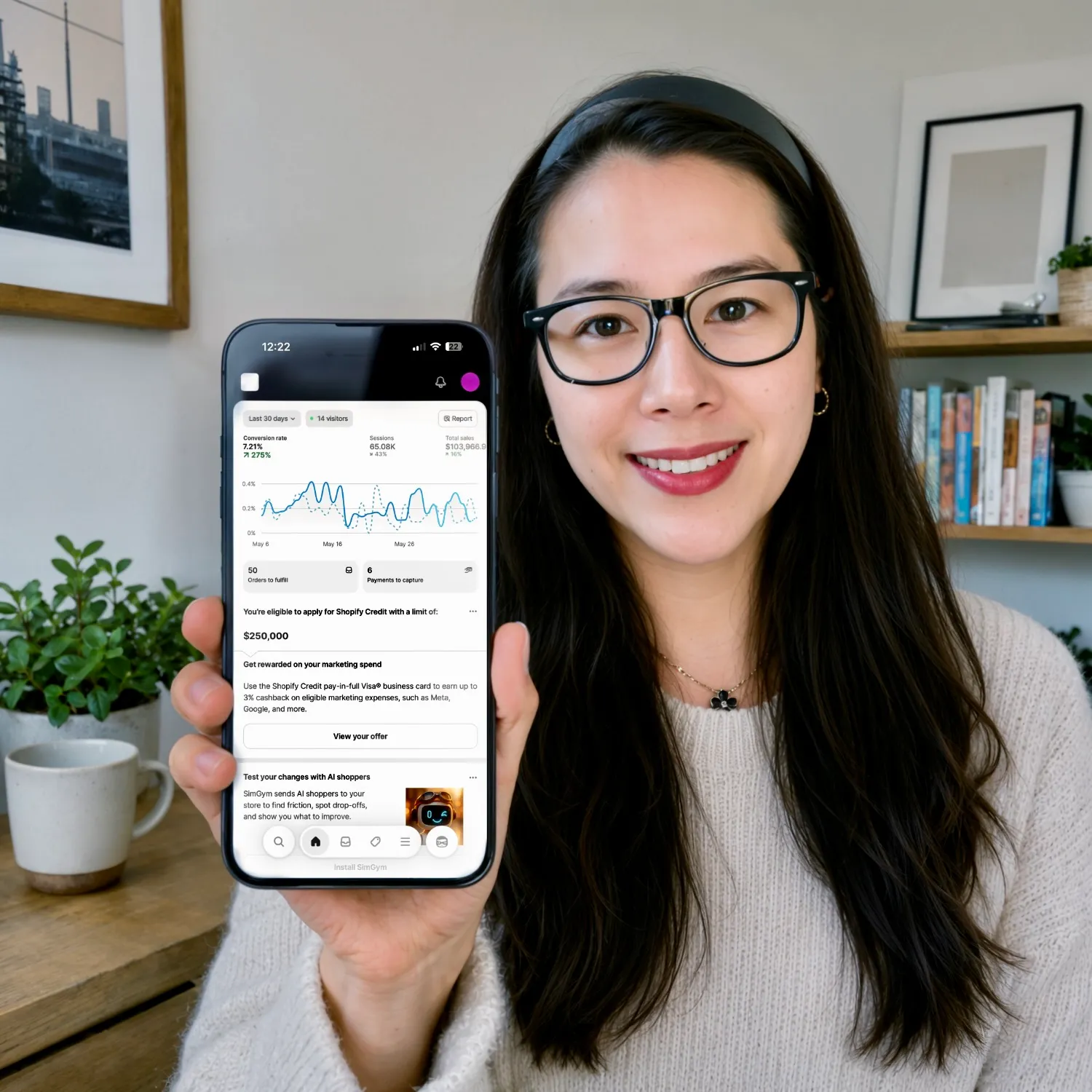 Founder holding a phone showing a Shopify analytics dashboard
